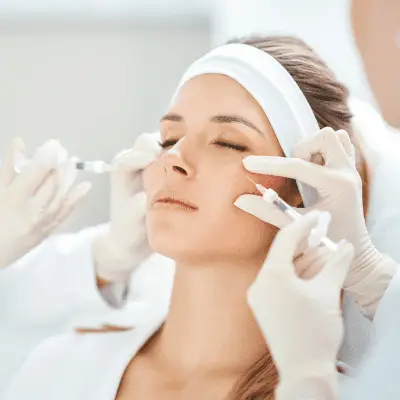 A woman receiving a cosmetic injection in her forehead from a healthcare professional at her home redesign consultation.