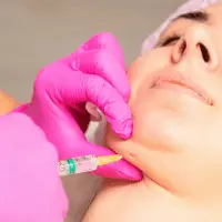 Aesthetician performing a cosmetic injection on a woman's face during a home redesign consultation.