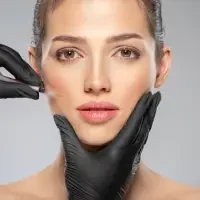 A woman in black gloves is getting facial injections for treatments.