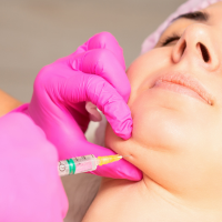 A woman receiving a facial treatment with a syringe injection for rejuvenation.